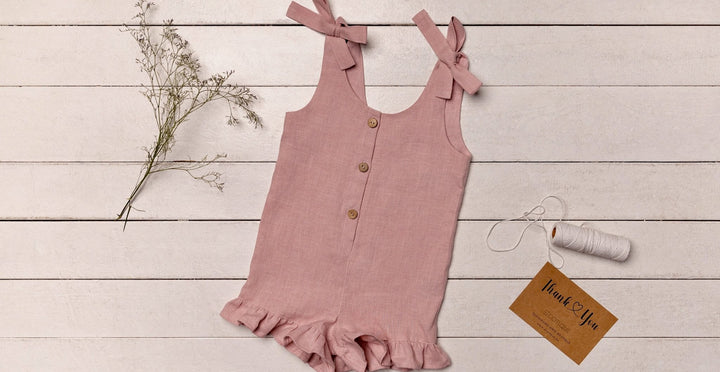 Adorable linen romper in soft pastel pink, designed for comfort and style, displayed with matching kids' accessories.